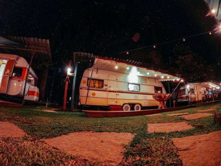 Low angle of caravans with luminous lights parked in camping yard at night